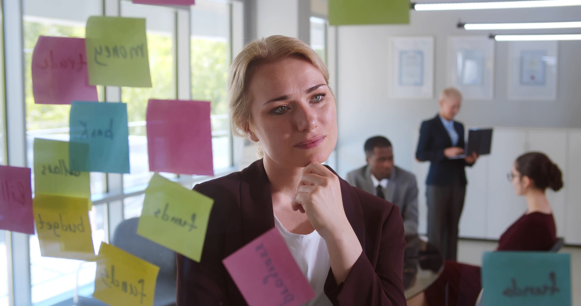 Confident young businesswoman writing on sticker with pencil and brainstorming.